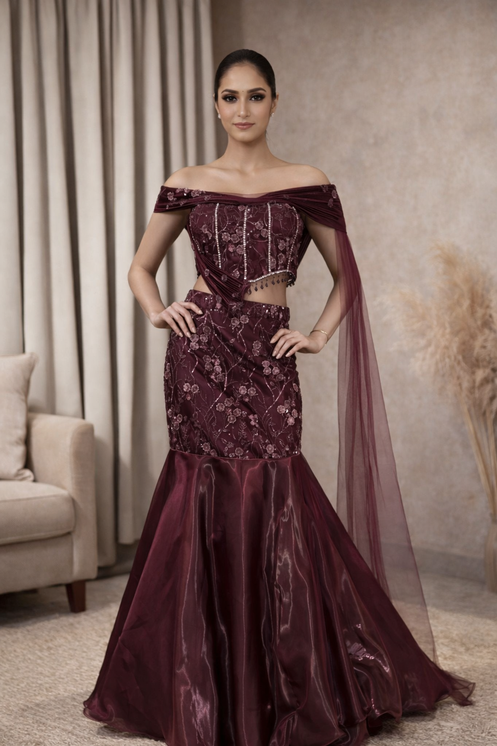 Woman wearing a burgundy evening gown with floral embroidery in a room setting.